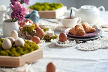 Fototapeta na wymiar Cozy elegant festive table decor for Easter in a light tone. handmade macrame products, eggs.