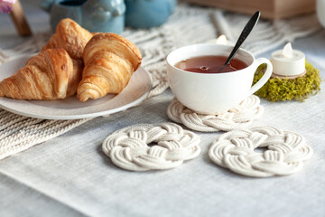 Beautiful cozy breakfast, croissants and tea, the table is decorated with macrame napkins