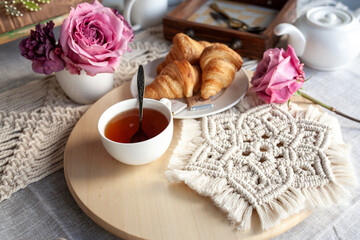 Beautiful cozy breakfast, croissants and tea, the table is decorated with macrame napkins