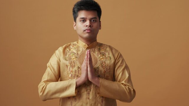 Handsome Indian man in national cloth doing meditation in the orange studio