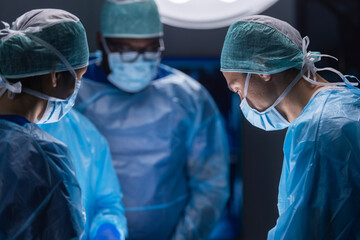 Multiracial team of professional medical surgeons performs the surgical operation in a modern...