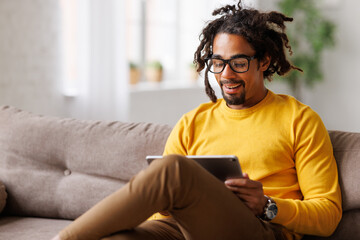 Young african american man with digital tablet and talking via video call during self-isolation