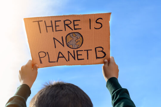 Boy With Unrecognizable Back Holding A Sign Towards The Sky That Reads 