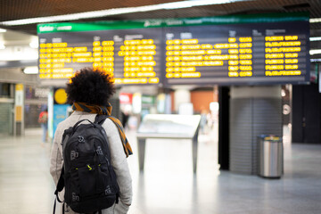 Young male traveler looking at departures and arrivals panel at airport or train station. Space for...