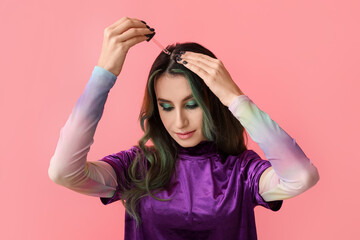 Young woman using serum for hair loss treatment on color background