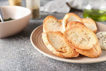 Plate of tasty croutons on grey background