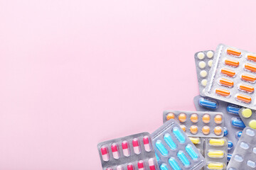 Colorful pills in blisters on pink background