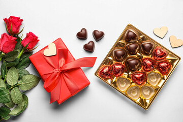 Composition with tasty heart-shaped candies and flowers on white background