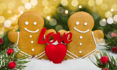 Valentine's Day holiday concept. Festive composition with couple gingerbread men, red heart and the word LOVE on a snowy background. Close-up. Selective focus.