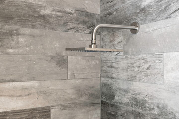 Detail of modern chrome shower head with faux wood tile. 