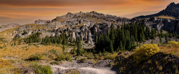 An unpaved road winding through the fir trees and rock hoodoos in the San Juan mountains near Ouray...