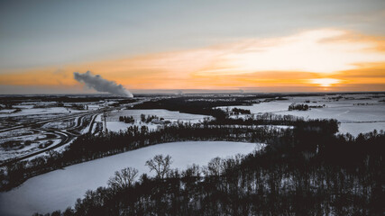 Black, white, and orange sunset over winter landscape with power planT