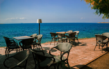 rustic cage patio rest zone with furniture chairs and table for breakfast, waterfront walking space along the sea in south European region