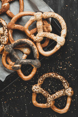 Fresh prepared homemade soft pretzels. Different types of baked pretzels with seeds on a black background