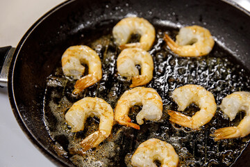 Fried shrimp on pan, preparing dish with seafood.