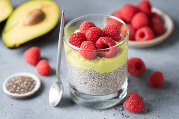 Healthy dessert Chia seed pudding with raspberries and avocado in glass on concrete table, closeup view