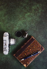 Vintage 35mm film camera, old book and photographic film on green texture background with copy space