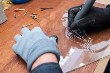 A craftsman does glass engraving with a rotary tool