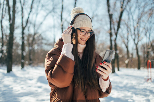 Pretty young woman listening music and enjoy winter outdoors
