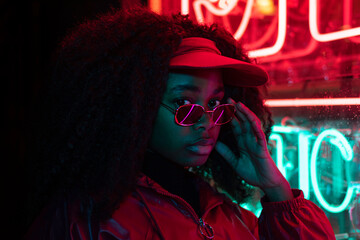 Street fashion young girl with sunglasses, neon light red and blue, nightlife and trendy lifestyle