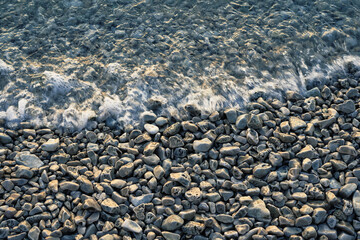 Pebble stones by the sea. Silky waves of sea.