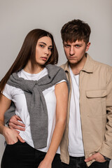 beautiful fashionable stylish girl and a fashionable guy in a stylish white T-shirt with a sweater and jacket are standing in the studio