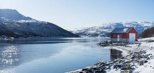 View along the fjord with a red boathouse at Nordfjordsbotn, Kvaloya, Tromso, Norway