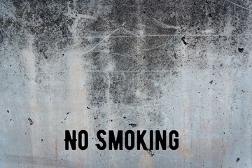 Gray wall, thick concrete background with natural cement texture with space for text. With text "no smoking"