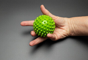The hand of an elderly woman is squeezing a relief ball. Exercises for hands and fingers. Rehabilitation