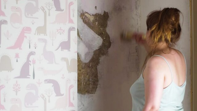 girl glues children's wallpaper on the wall, smears the wall with glue with a brush