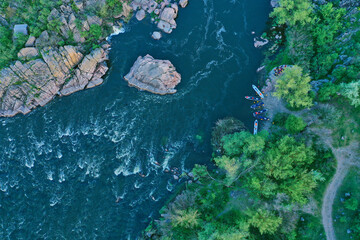 Aerial view of the winning rowers disembarking from boat races on the river. Rowers after the race gathering to award the winners of the competition. Racing boats are moored to the river bank. © monvideo