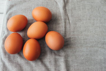 Several chicken eggs lie on kitchen towel. Preparation for cooking, for coloring for Easter. Lay out ingredients. Copy space