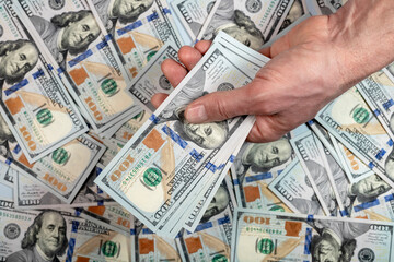 Hand giving cash money closeup over dollars heap. Bribery and loan concept.