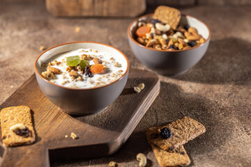 Healthy lifestyle breakfast, granola bowl with dried fruits and milk on brown wooden table background, organic food