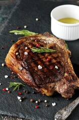steak grilled beef entrecote on bone on dark slate background. stone slate for feeding meat.
