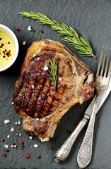 steak grilled beef entrecote on bone on dark slate background. stone slate for feeding meat.