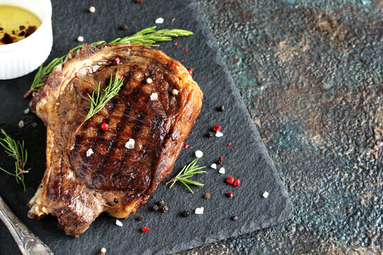 steak grilled beef entrecote on bone on dark slate background. stone slate for feeding meat.