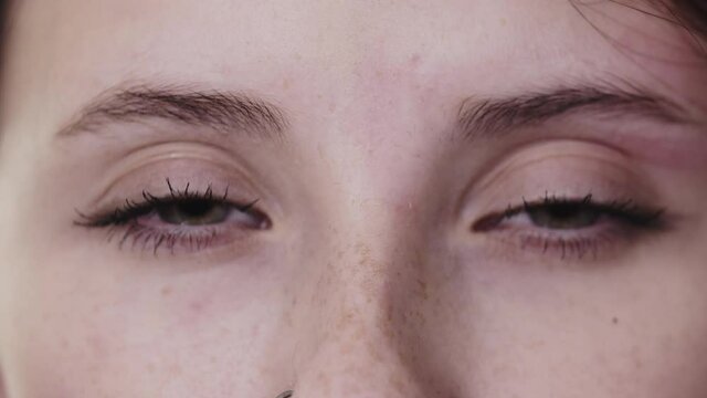 Waxing small little hairs in between the eyebrows of beautiful woman with grayish green eyes