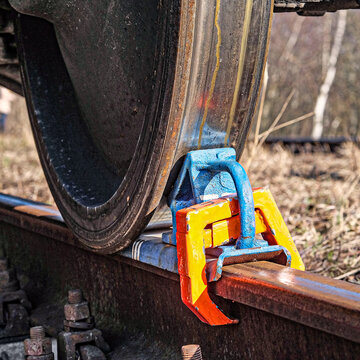 Rusty and polished freight train wheel on railroad track. Train shoe propped wheel train.