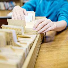 Librarian woman searches something in card catalog