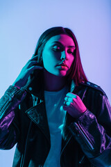 Color fashionable portrait of pretty young American girl model in fashion outerwear with a stylish leather jacket in blue and pink lights