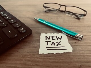 Text new tax with pen, calculator and glasses on office desk