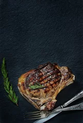 Rolgordijnen steak grilled beef entrecote on bone on dark slate background. stone slate for feeding meat. © shabbydecor