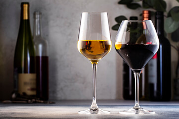 Wines assortment. Red, white, rose wine in glasses and bottles on gray table background. Wine bar, shop, tasting concept