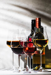 Red, rose and white wine glasses set on gray table background. Wine tasting. Hard light and harsh shadows