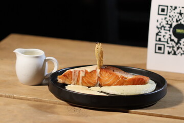 Saumon with cheese sauce on black plate and tortilla on top