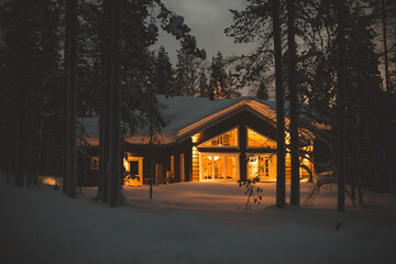 A view of cozy wooden scandinavian cabin cottage chalet house covered in snow near ski resort in...