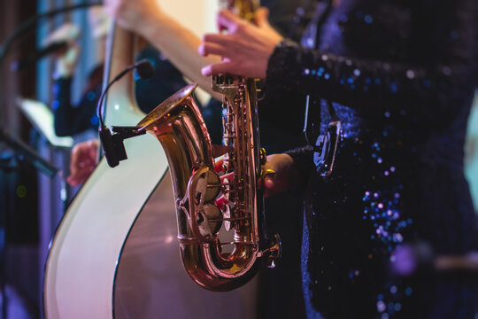 Concert view of a female saxophonist, professional saxophone player with vocalist and musical during jazz band performing