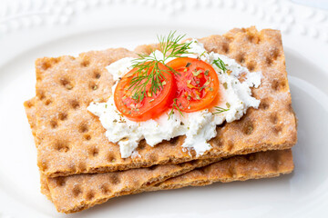 Fresh rye crispbread with cream cheese and vegetables isolated on white