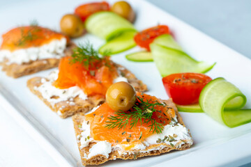 Sandwich with smoked salmon and cream cheese on thin multi seed crispbread, garnished with olives.